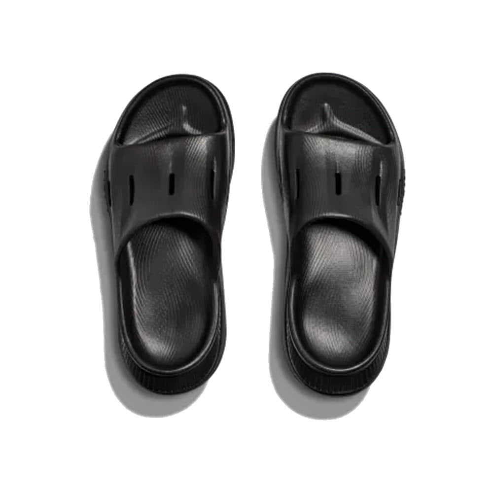 Hoka HOKA ORA RECOVERY SLIDE 3 BLACK - ADULT sandals feature open toes, raised arch support, and perforations on the upper strap offering foot-cradling comfort.