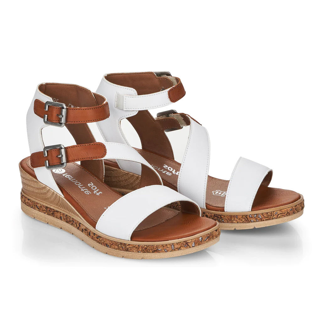 Remonte&#39;s REMONTE ASYMMETRICAL STRAPPY WEDGE WHITE for women features a white wedge heel sandal with adjustable ankle straps and buckles, and a decorative cork-patterned sole.