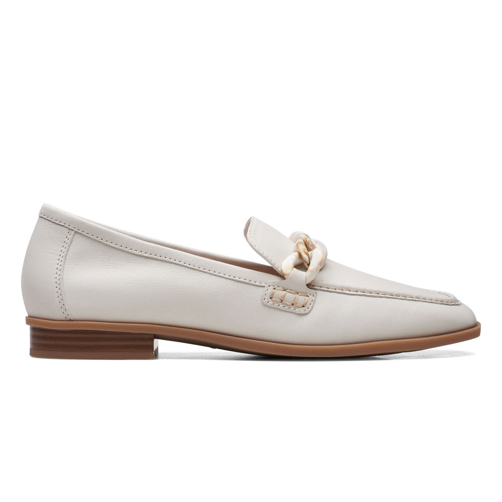 A side view of the Clarks Sarafyna Iris White women's loafer showcasing a white, tailored leather upper with a decorative vamp strap and a wooden low heel.