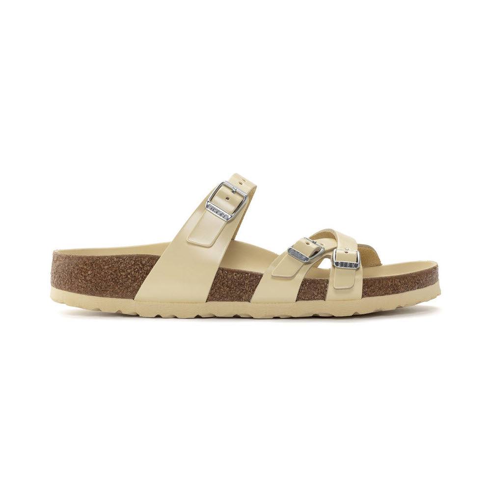 The BIRKENSTOCK FRANCA HEX HIGH SHINE BUTTER - WOMENS features beige leather straps, a brown cork-latex footbed, and an off-white outsole. It boasts two adjustable buckles on the top straps, reminiscent of classic Birkenstock designs.