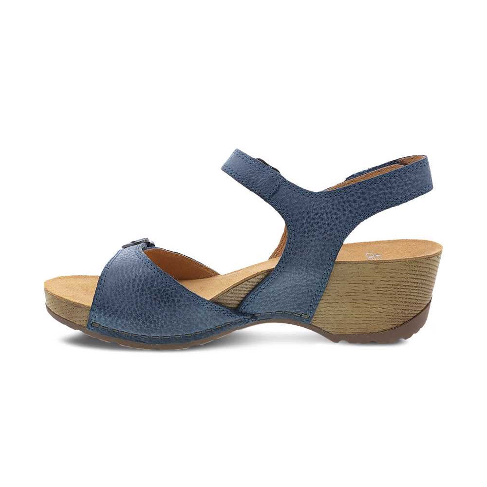 Introducing the Dansko Tricia Blue - Womens, a blue leather warm-weather sandal from Dansko. This stylish wedge heel sandal features an ankle strap, a wood-textured sole, and a contoured footbed for premium comfort.