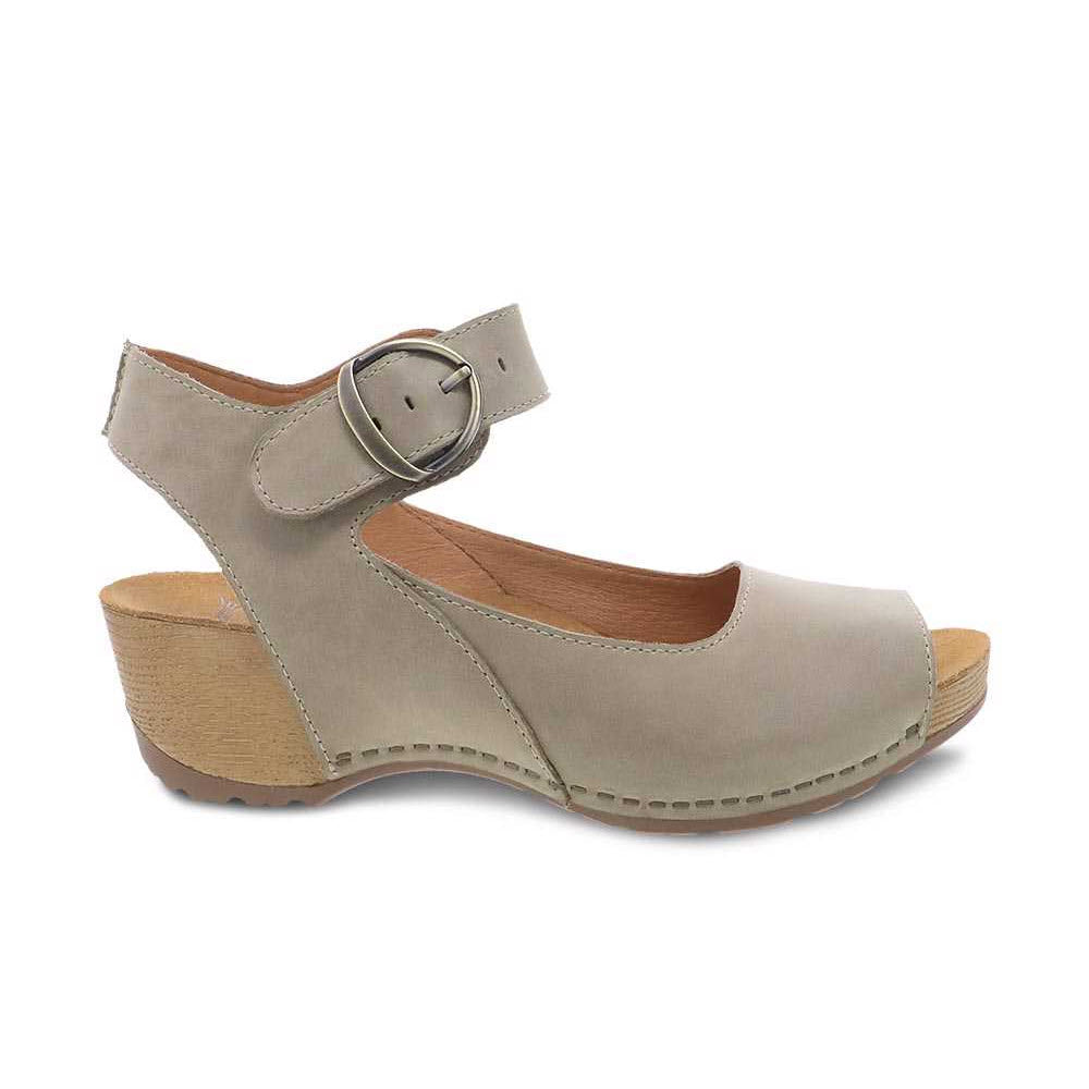 The DANSKO TIANA KHAKI NUBUCK for Women by Dansko is a beige closed-toe sandal with a low wedge heel, an adjustable ankle strap featuring a large buckle, and a contoured footbed.