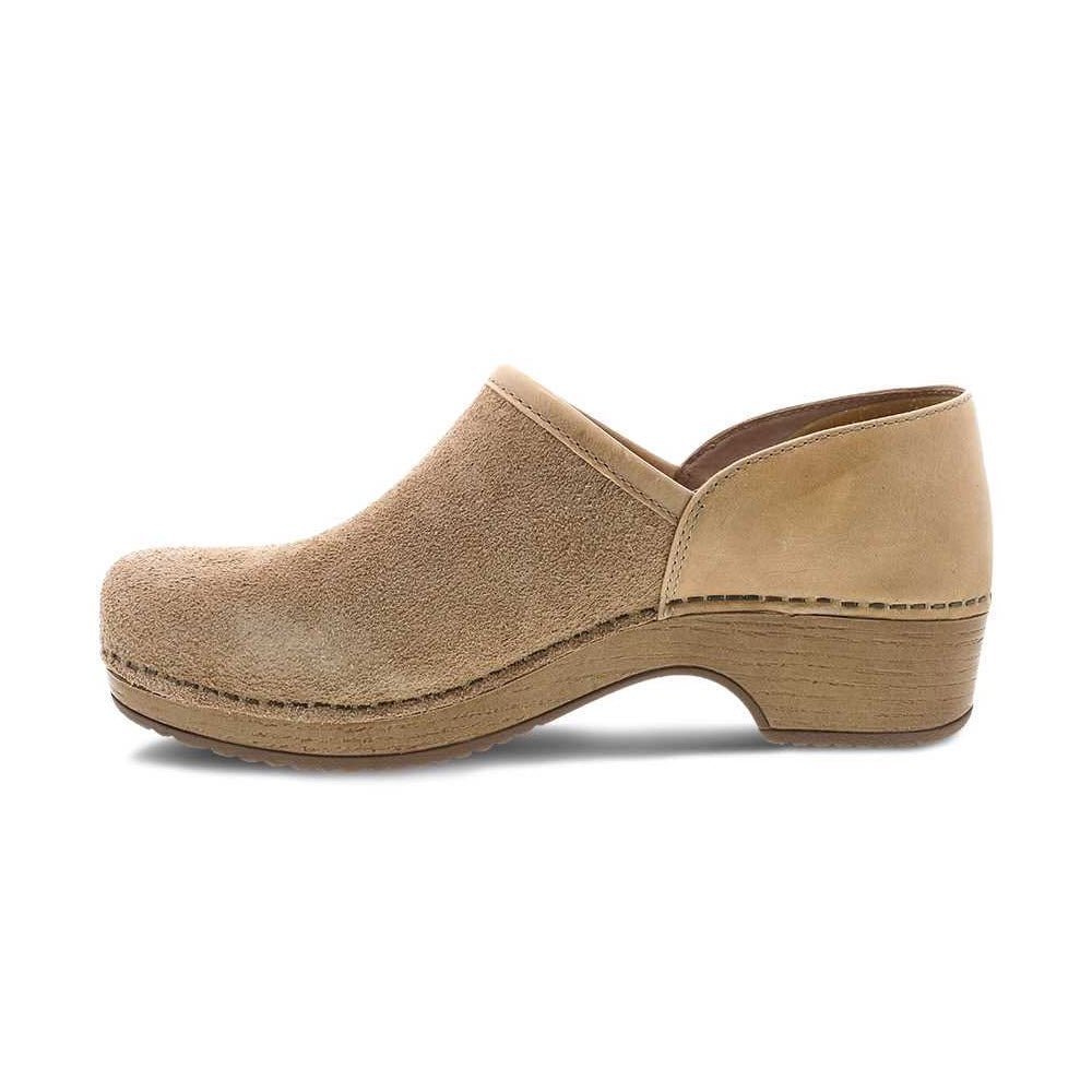 Side view of the Dansko Brenna Sand Suede for women, featuring a chunky wooden heel, closed toe, and casual slip-on design.