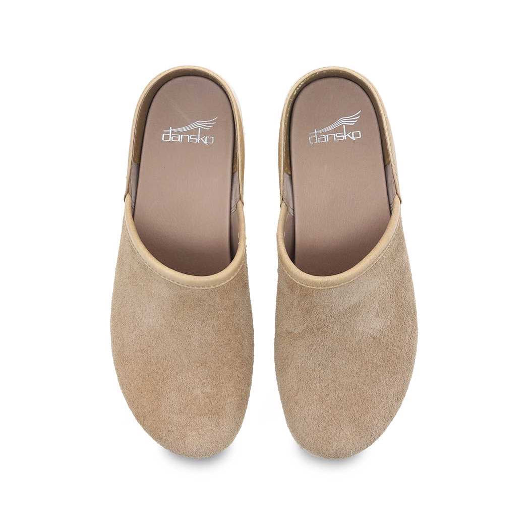 A pair of DANSKO BRENNA SAND SUEDE - WOMENS clogs, featuring tan suede and a brown inner lining, proudly displaying the Dansko brand on the insole. These casual slip-ons are designed for stain resistance and odor control, ensuring both comfort and practicality.