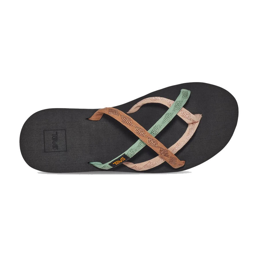 The Teva Women&#39;s Olowahu, also known as the TEVA OLOWAHU MAPLE SUGAR MULTI, features a single black flip-flop sandal with an elegant brown and green crisscross strap design, adorned with a yellow &quot;Teva&quot; logo on the strap for added style and comfort.