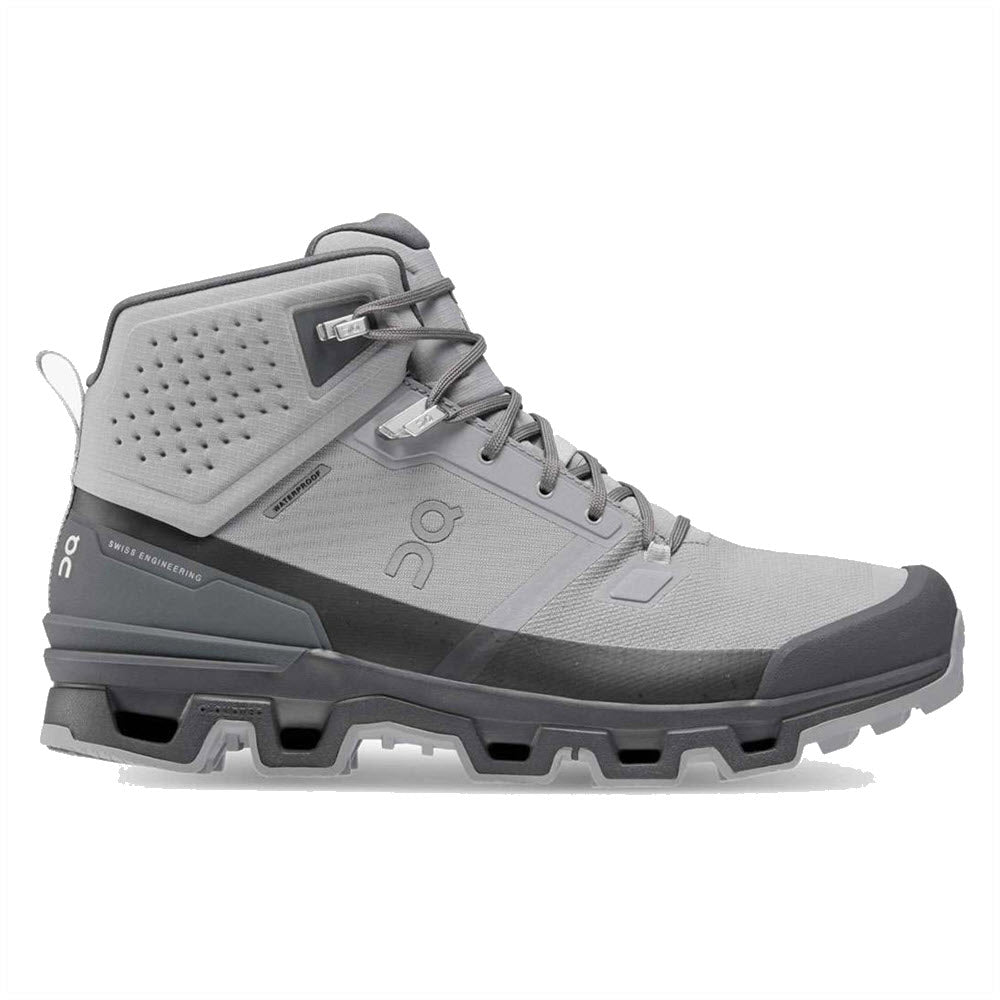 A gray and black high-top hiking boot with a perforated upper section, lace-up design, and a rugged sole featuring the Swiss-engineered FlexLock system is shown against a white background. This is the ON CLOUDROCK WATERPROOF ALLOY/ECLIPSE - MENS by On Running.