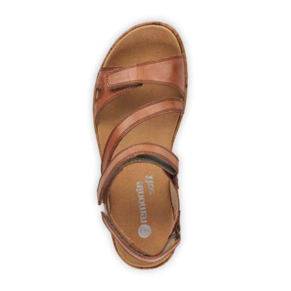 One REMONTE COMFORT Z STRAP COGNAC sandal features a brown, open-toe design with adjustable ankle straps and a cushioned insole, viewed from above. The leather wedge heel offers both style and comfort. The insole proudly displays the brand name &quot;Remonte.