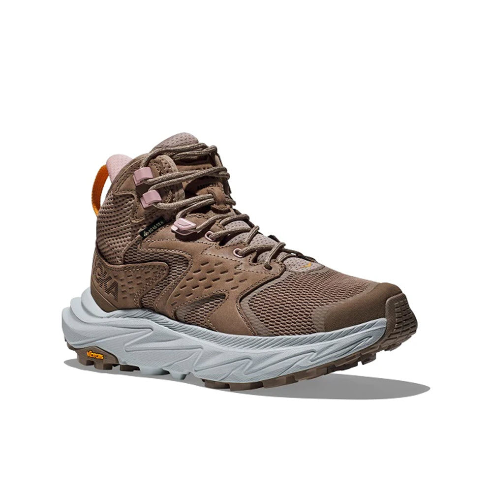 The Hoka Anacapa 2 Mid GTX in Dune/Ice Flow - Women&#39;s features a brown upper with a grey sole, viewed from a side angle. This hiking boot boasts mesh fabric, a lace-up design, and a high ankle collar along with an ultra-ventilated upper to keep your feet cool.