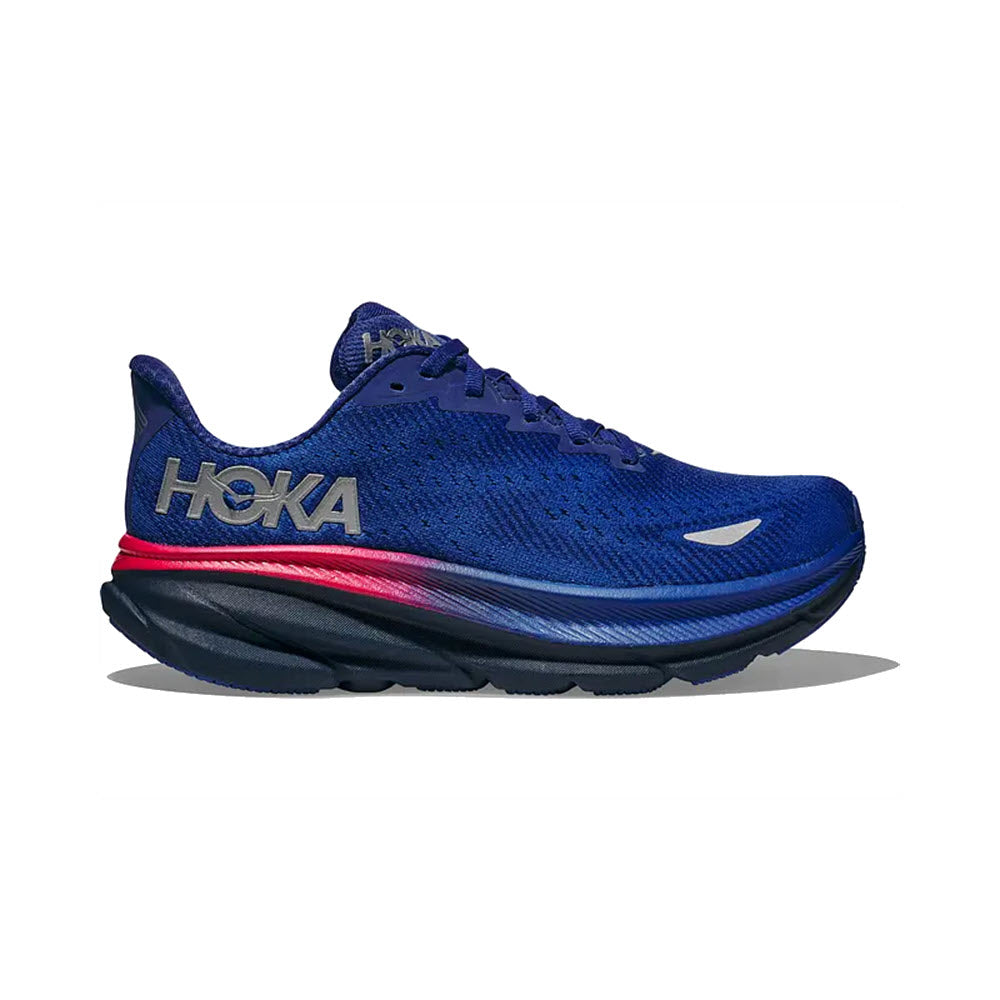 The HOKA CLIFTON 9 GTX DAZZLING BLUE/EVENING SKY for women features a thick, cushioned sole and the Hoka logo on the side. It includes reflectivity for low-light runs, with a midsole showcasing gradient colors from red to black.