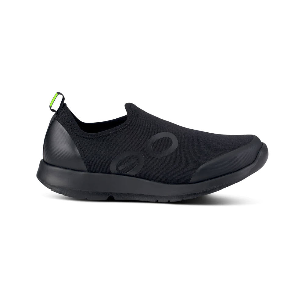 The OOFOS OOMG SPORT BLACK - WOMENS by Oofos is a black slip-on athlete-inspired recovery shoe that incorporates OOfoam technology. It features a green tab on the heel and two round designs on the side, all set against a white background.