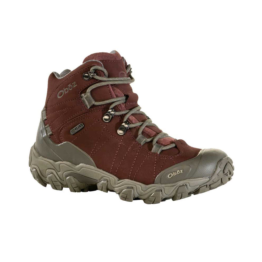 A dark red and grey hiking boot with rugged treads, lace-up front, and reinforced toe and heel sections. The brand name &quot;Oboz&quot; is visible on the side and tongue. Crafted for durability and support, these OBOZ BRIDGER MID B-DRY PORT - WOMENS boots excel in trail performance, making them perfect for your outdoor adventures.