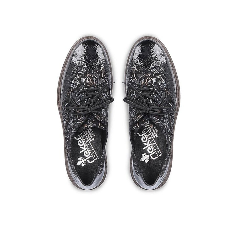 A pair of RIEKER MODERN TAILORED BROGUE BLACK META - WOMENS by Rieker, featuring intricate patterns and visible brand logos inside, viewed from above on a white background.