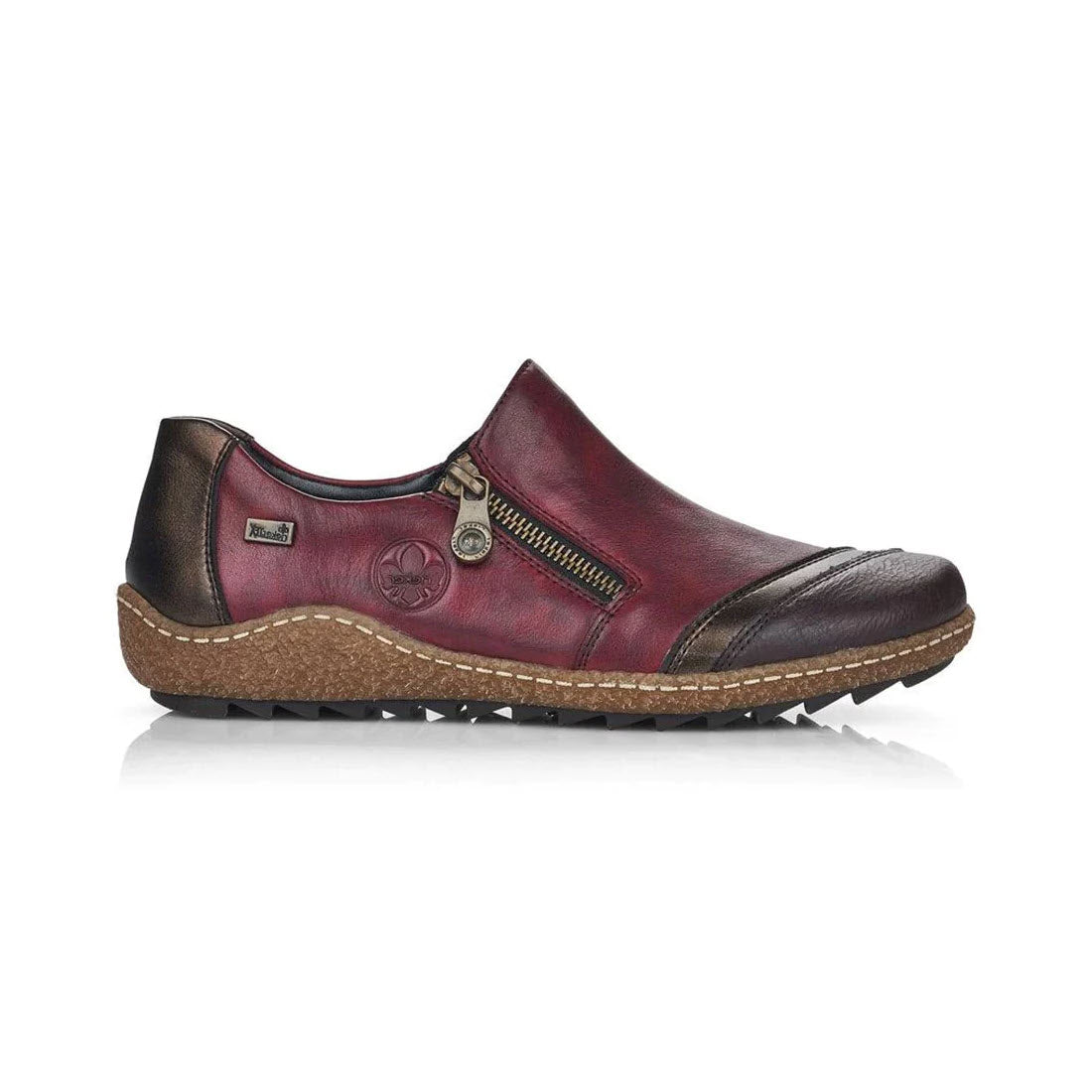 The RIEKER EURO CITY SLIP ON WITH ZIP WINE - WOMENS is a casual shoe for women, featuring a red and brown leather design with a side zipper, textured rubber sole, and Rieker Tex membrane for added comfort.