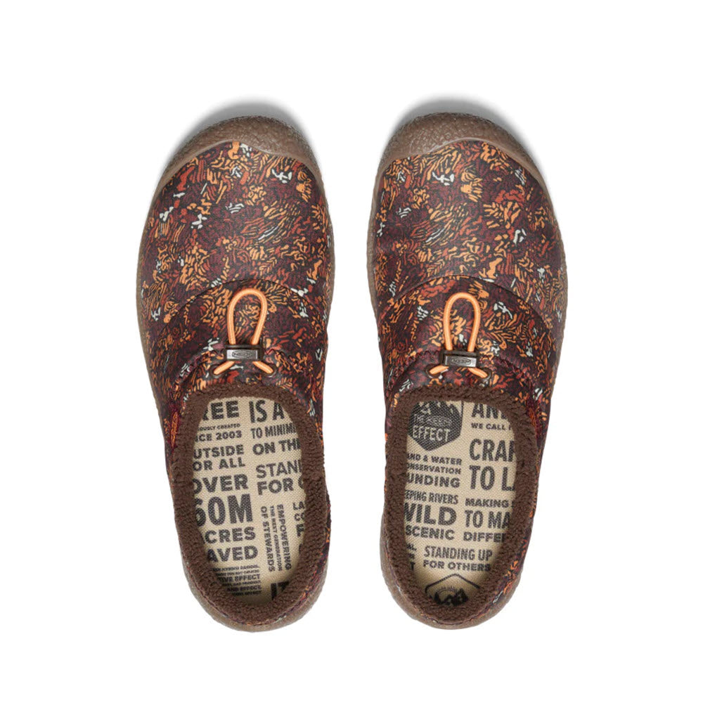 Top view of KEEN HOWSER III SLIDE ANDORRA CAMO women&#39;s slip-on shoes by Keen, showcasing a brown and red leafy pattern with orange bungee elastic laces. The insoles feature printed text and images that promote sustainability and conservation efforts.