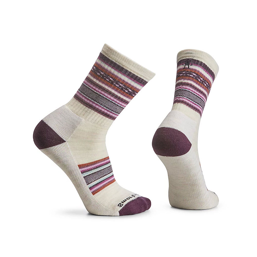 Two cream-colored Smartwool SMARTWOOL REGARITA CREW SOCKS MOONBEAM - WOMENS with purple and multicolored stripe patterns on top, showcased from different angles, offer superior odor resistance and exceptional temperature regulation.