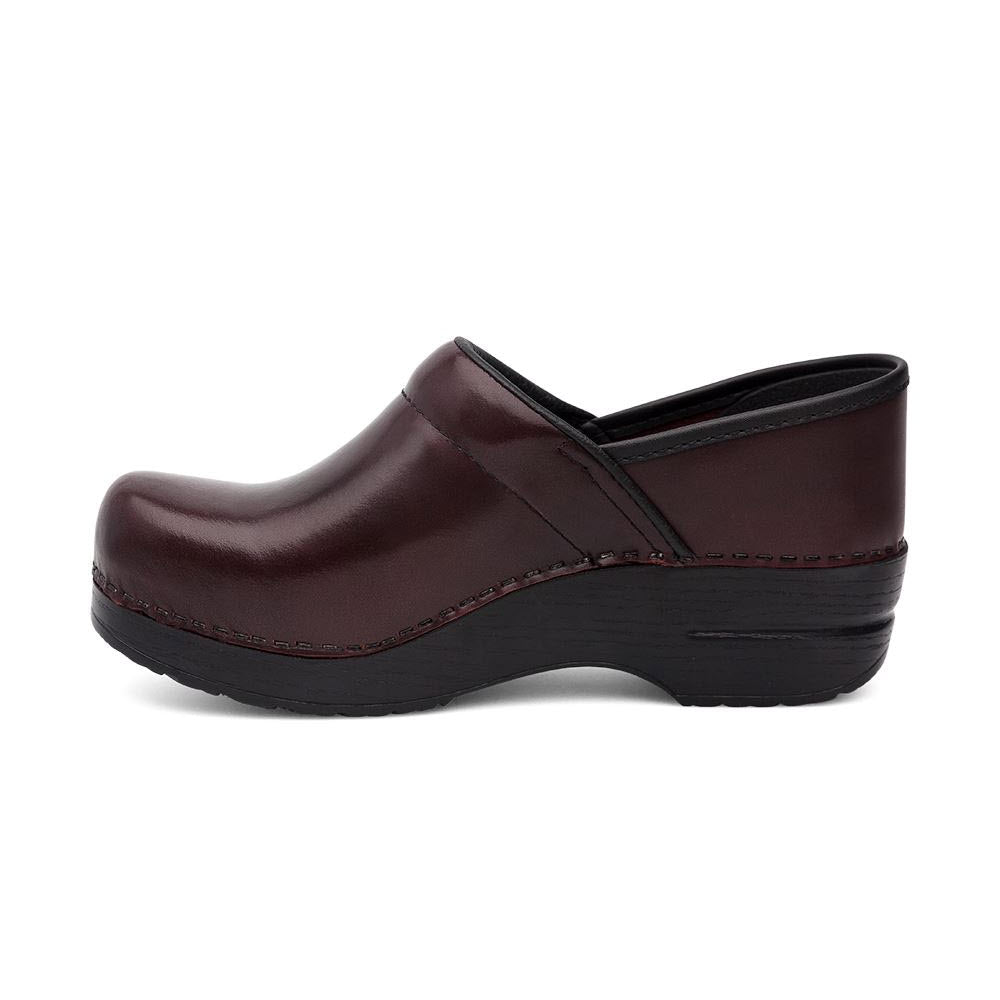 Side view of a single dark brown slip-on clog with a black sole and slight platform heel, featuring Dansko&#39;s DANSKO PROFESSIONAL CORDOVAN CABRIO - WOMENS signature anti-fatigue rocker bottom for unparalleled comfort.