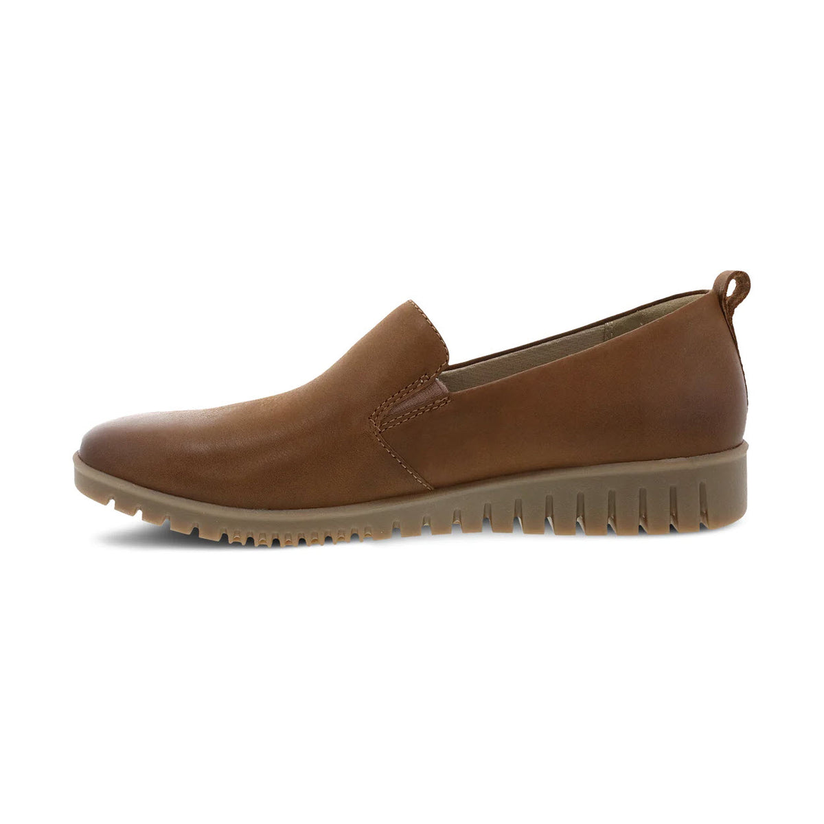 The DANSKO LINLEY TAN BURNISHED slip-on shoe for women, by Dansko, is crafted from buttery soft leathers and features a rugged, ribbed sole and a small loop at the heel. It includes a molded arch shape for enhanced comfort, viewed from the side.