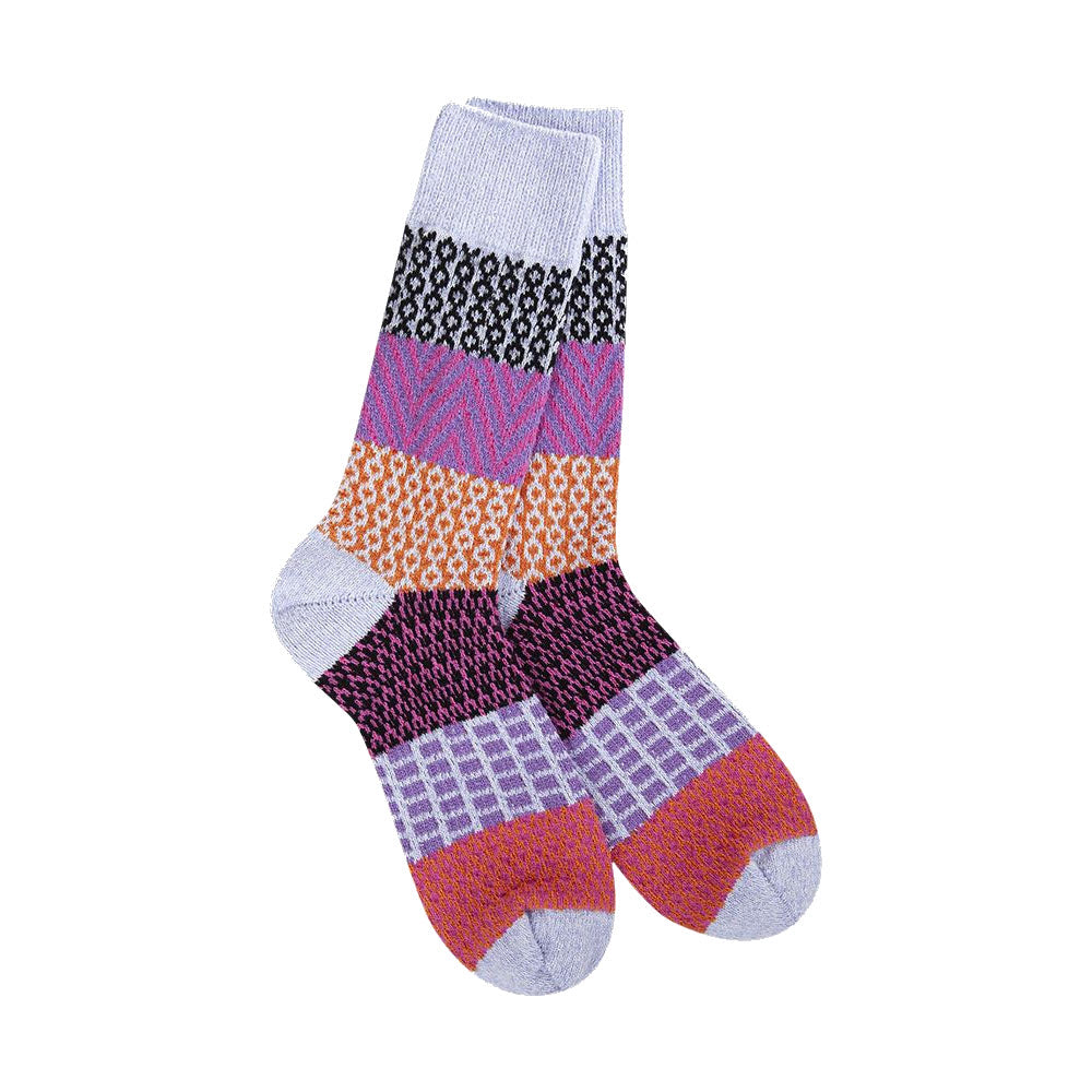 A pair of WORLDS SOFTEST GALLERY CREW SOCKS LAVENDER - WOMENS from Worlds Softest, featuring purple, orange, black, and white sections with various geometric designs.