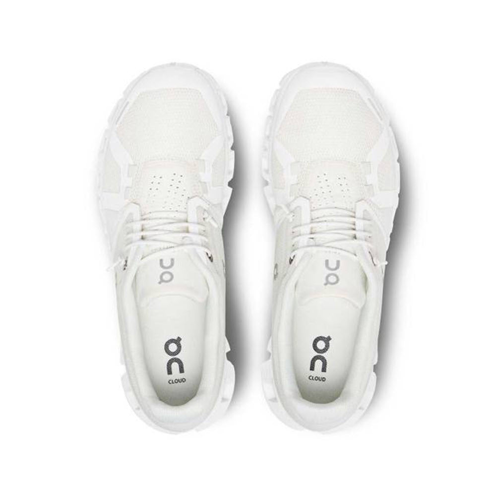 A pair of ON RUNNING CLOUD 5 UNDYED WHITE - WOMENS viewed from above, featuring the brand logo &quot;On Running&quot; and the word &quot;Cloud&quot; on the tongues, designed for On-fans seeking improved fit and more comfort.