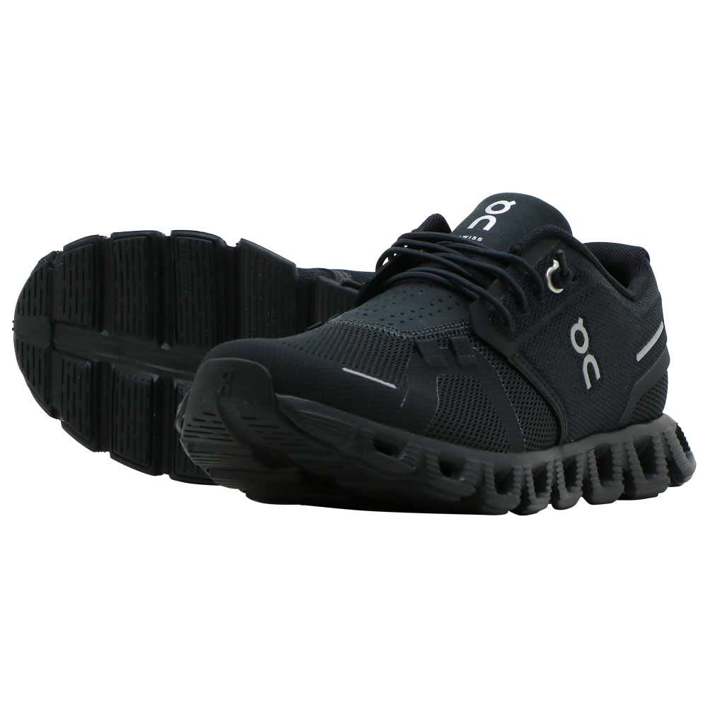 A pair of ON RUNNING CLOUD 5 ALL BLACK - WOMENS with mesh detailing and a unique outsole design, featuring the On Running logo on the tongue and sides, offering improved fit for more comfort all day.