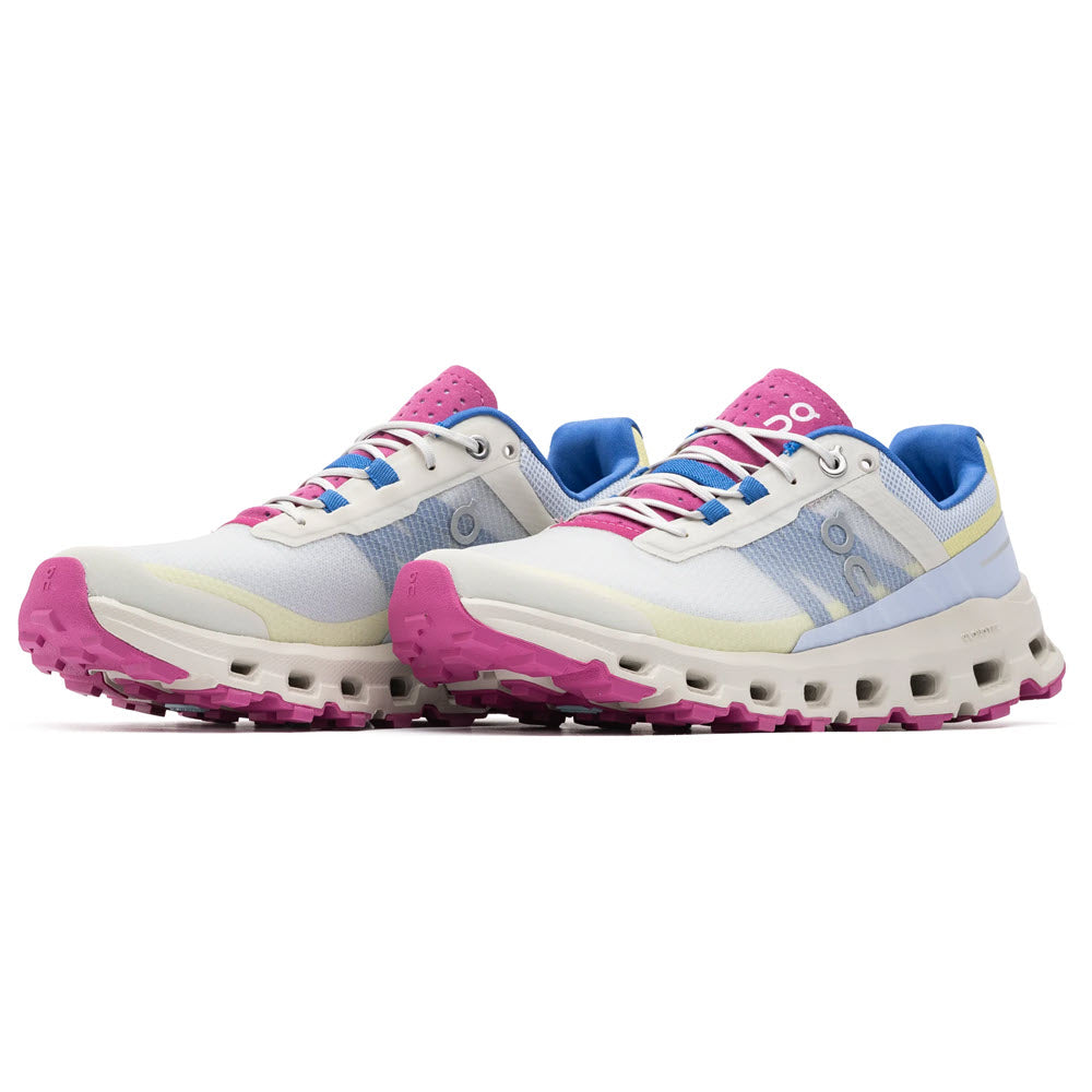 The ON RUNNING CLOUDVISTA HEATHER/RHUBARB - WOMENS sneakers by On Running, featuring a striking combination of white with pink outsoles, blue and pink accents, and white laces, are perfect for trail runners seeking both style and functionality during their outdoor adventures. Displayed on a clean white background.