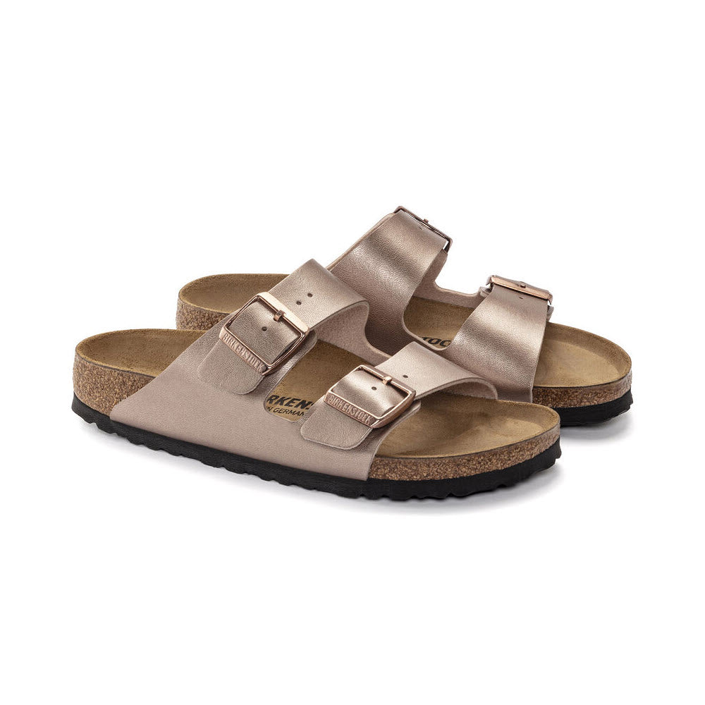 A pair of Birkenstock BIRKENSTOCK ARIZONA METALLIC COPPER BIRKOFLOR - WOMENS sandals with two adjustable buckle straps and a comfortable contoured cork-latex footbed.