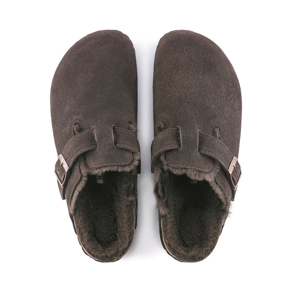 A pair of BIRKENSTOCK BOSTON SHEARLING MOCHA SUEDE - WOMENS with adjustable buckles and a cozy shearling lining, viewed from above, perfect for casual wear.