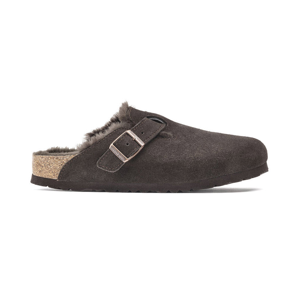 A single BIRKENSTOCK BOSTON SHEARLING MOCHA SUEDE - WOMENS clog with a cork sole and metal buckle strap, featuring a contoured cork footbed for added comfort. Side view.