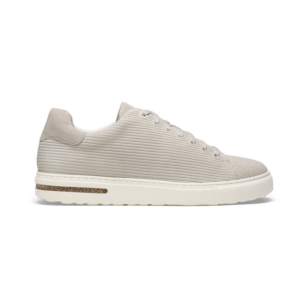 Side view of a single beige sneaker with a white sole, featuring an embossed suede upper and lace-up design, offering support from the Birkenstock BEND CORDUROY ANTIQUE WHITE SUEDE - WOMENS.