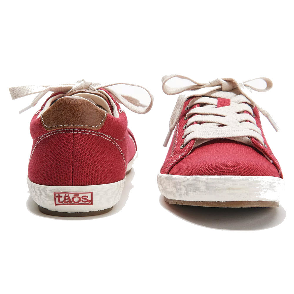 A pair of TAOS STAR BURST RED women&#39;s canvas sneakers featuring white soles, tan laces, and fabricated leather trim. The back heel displays a patch with the brand name &quot;Taos.