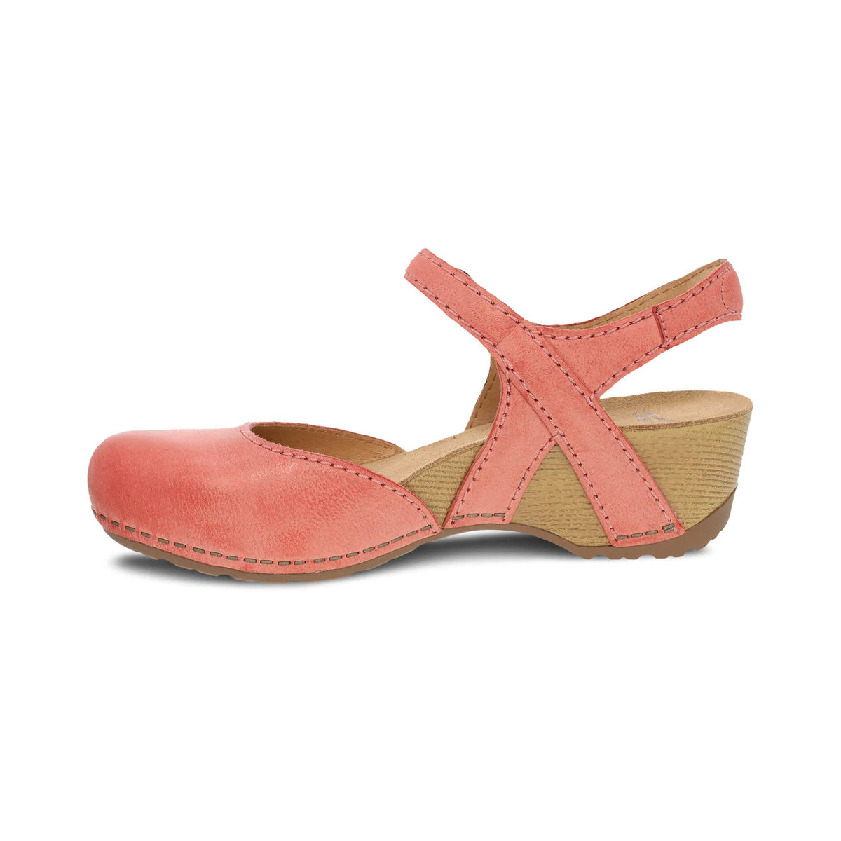 The Dansko Tiffani Coral women&#39;s shoe is a coral pink Mary Jane featuring crisscross straps and a low, chunky wooden heel, making it perfect for spring fashion.