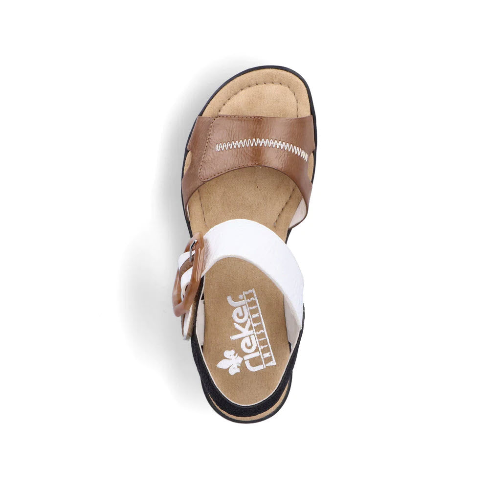 Top view of the Rieker Big Buckle Wedge Tan Multi sandals for women, highlighting the brown and white leather straps, a cushioned beige insole, and a tan buckle, set against a white background.