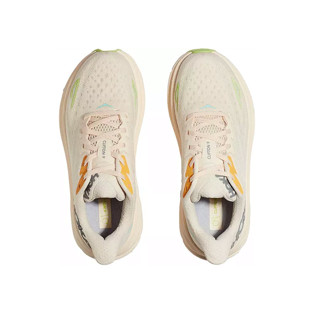 Top view of a pair of Hoka Clifton 9 Vanilla/Astral women&#39;s running shoes, adorned with yellow and green accents and &quot;Clifton 9&quot; on the tongues. These shoes feature an improved outsole design and responsive new foam, enhancing performance.