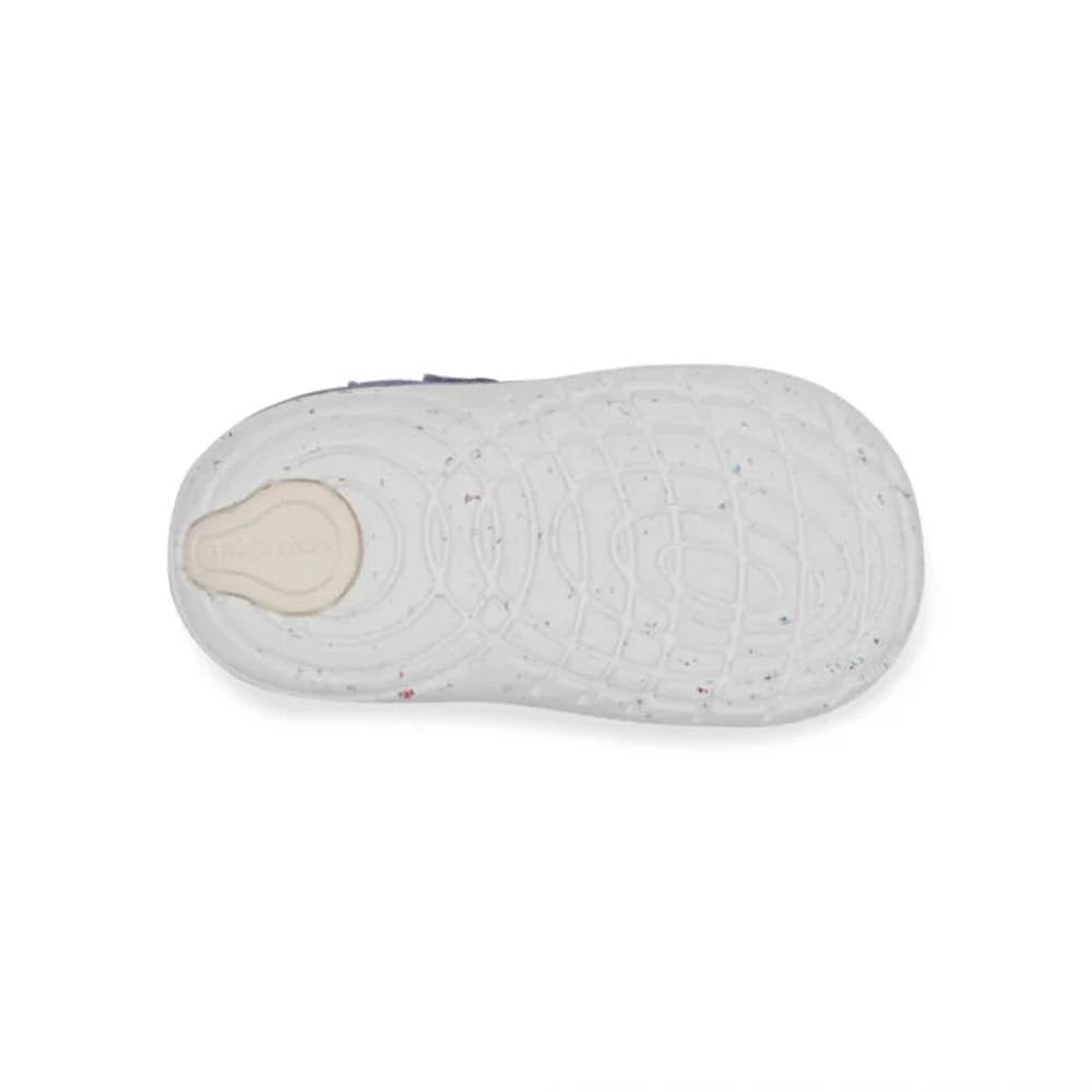 Top view of a single white shoe sole with a textured pattern and speckled markings. The heel area has a beige circular pad. Made from recycled materials, it also features a memory foam interior for added comfort. This is the STRIDE RITE SM SPROUT BLUE - KIDS from Stride Rite.