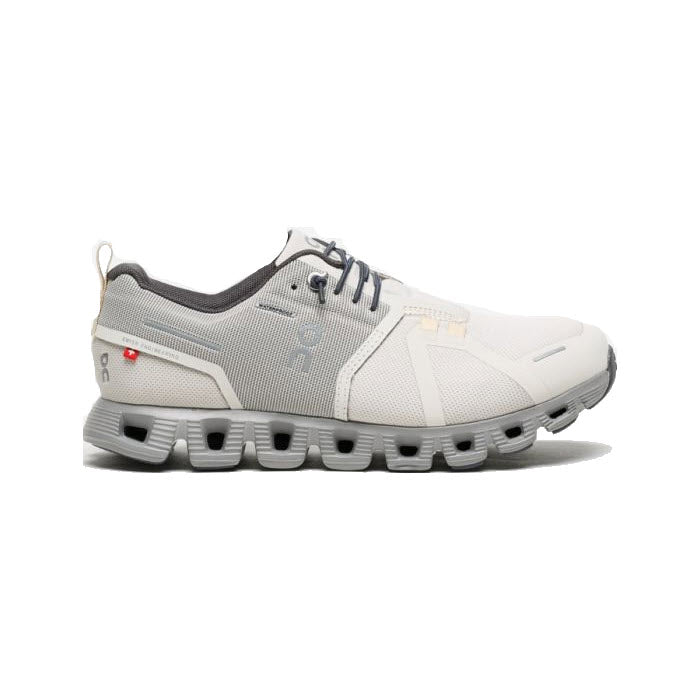 The ON Cloud 5 Waterproof Pearl/Fog for women by On Running is a white and grey athletic sneaker featuring a speed-lacing system, a mesh upper, CloudTec cushioning, and a unique segmented sole design.