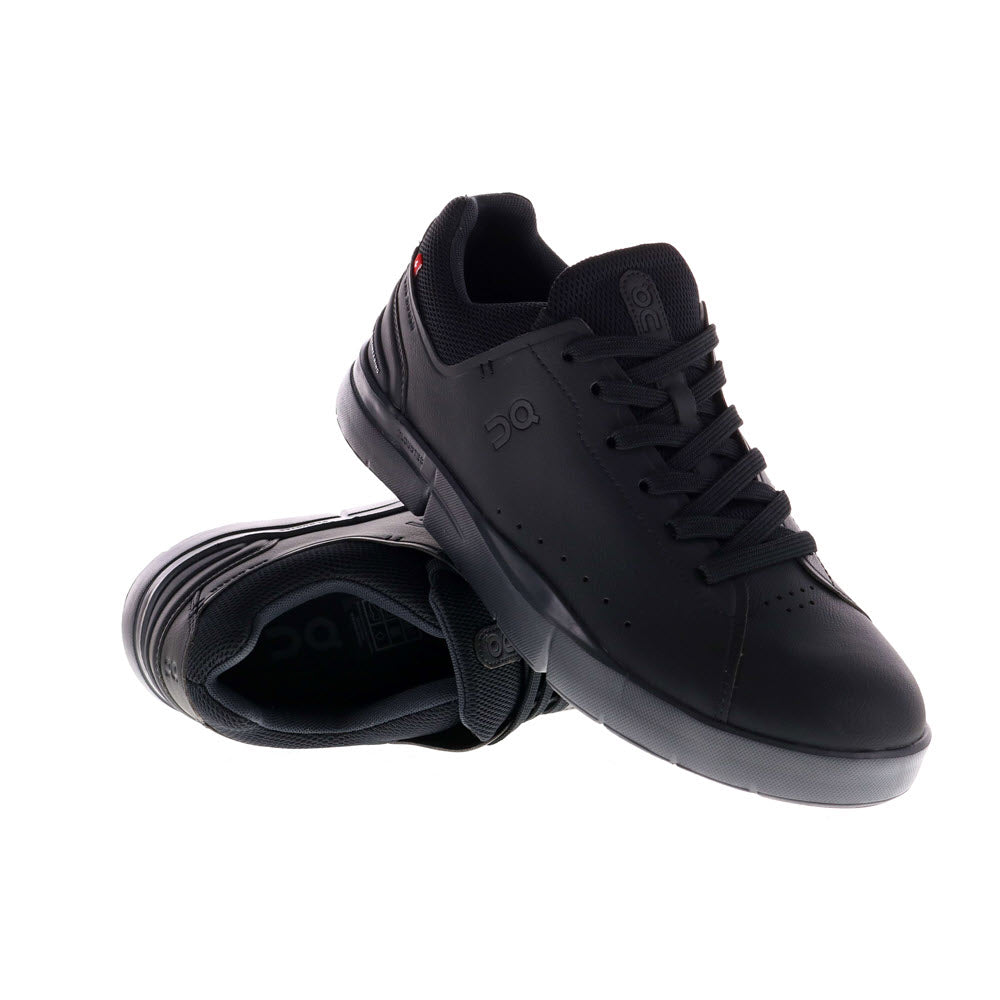 A pair of black lace-up sneakers with rubber soles, featuring CloudTec cushioning for ultimate comfort, one standing upright and the other tilted sideways, on a white background. Product Name: THE RODGER ADVANTAGE ALL BLACK - WOMENS Brand Name: On Running