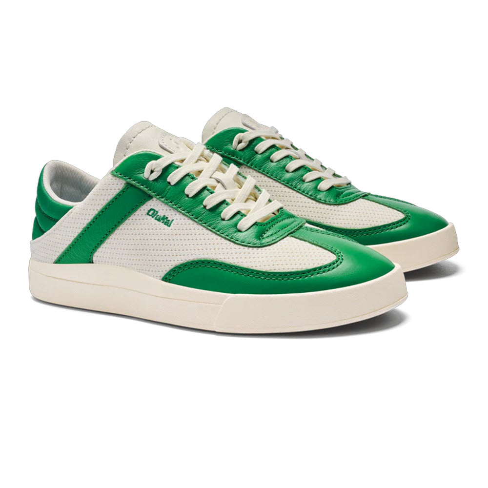 The Olukai Kilea Off White Bamboo sneakers for women, from the brand Olukai, feature white court styling with green accents and laces. They are designed with perforated detailing and white soles, along with green branding on the side. These sneakers promise cloud-like comfort, perfect for those who enjoy a beach lifestyle.