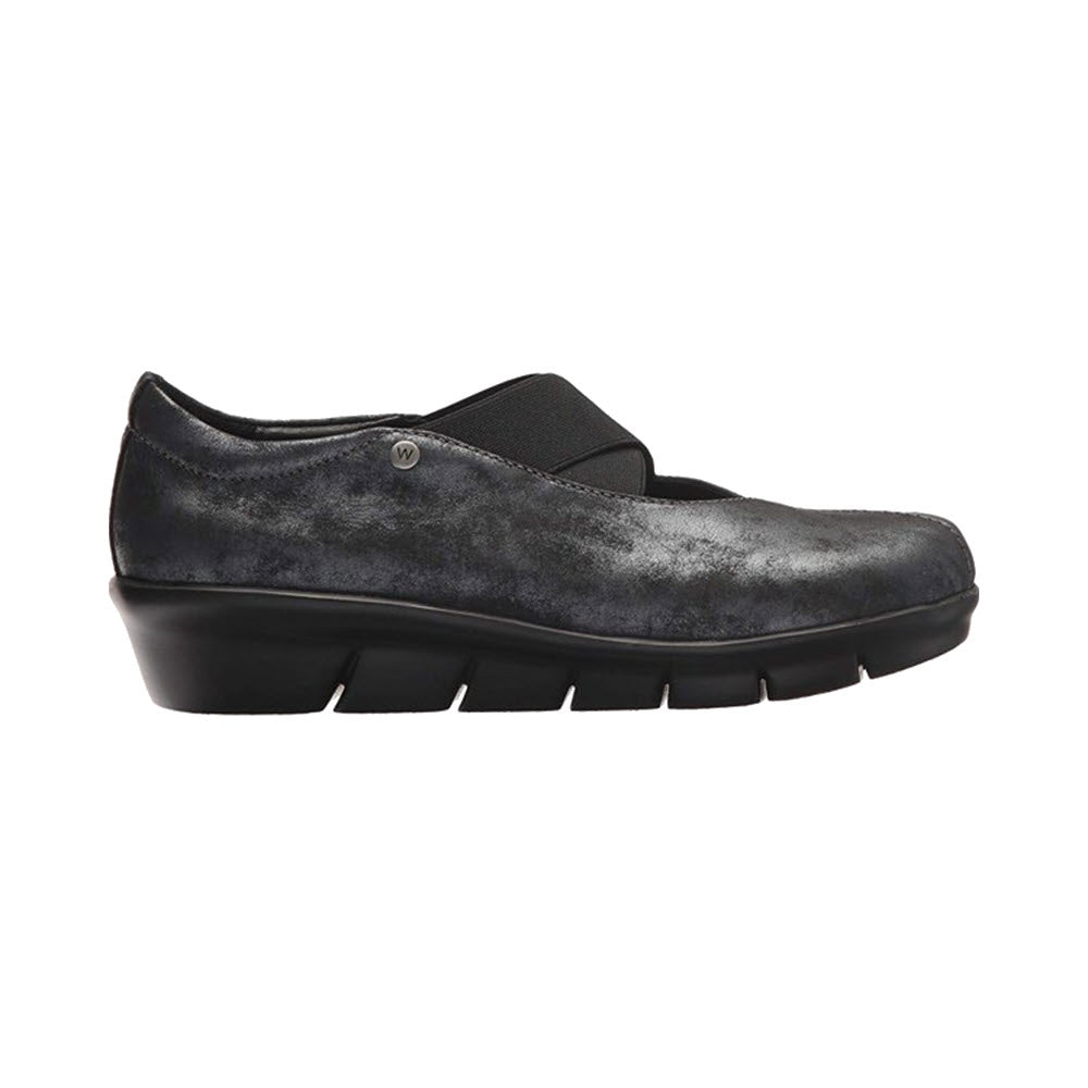 Side view of a single WOLKY CURSA AMALIA NUBUCK BLACK - WOMENS slip-on shoe with a low wedge heel and a cross-over elastic band on the upper. The supportive shoe features a lightly textured, matte finish and a memory foam insole for added comfort.