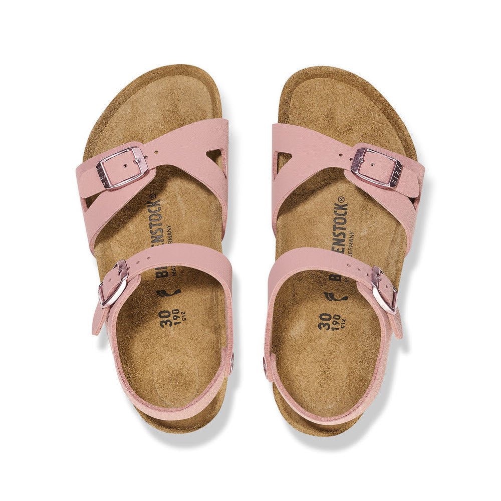 A pair of Birkenstock BIRKENSTOCK RIO PINK CLAY BIRKIBUC - KIDS with a contoured footbed and adjustable ankle strap, featuring cork soles, are shown from the top view.
