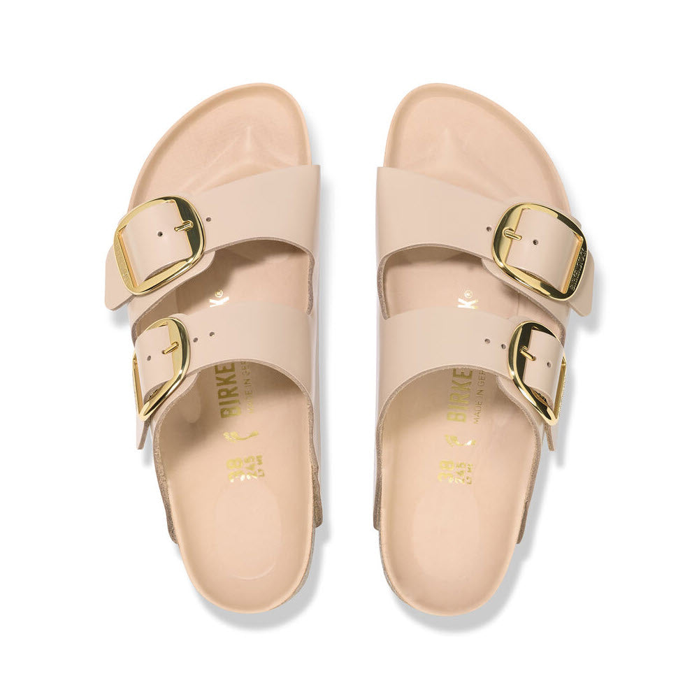 A pair of women&#39;s beige Birkenstock sandals in the Arizona Big Buckle High Shine design, made from natural leather, featuring two gold buckles.