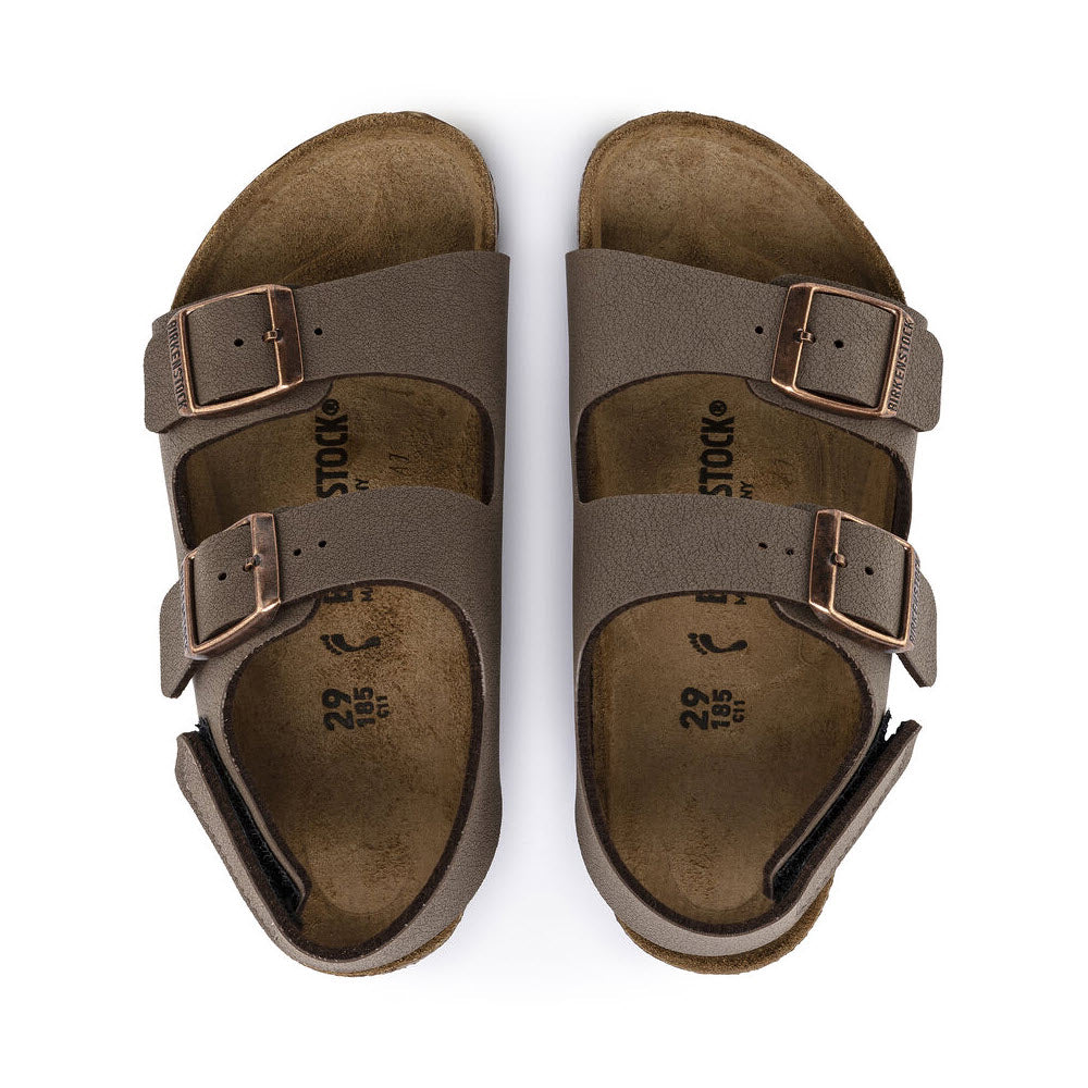 A pair of brown Birkenstock BIRKENSTOCK MILANO HOOK &amp; LOOP MOCHA BIRKIBUC - KIDS with adjustable buckles. The footbeds are contoured and appear well-worn, perfect for kids&#39; footwear needs.