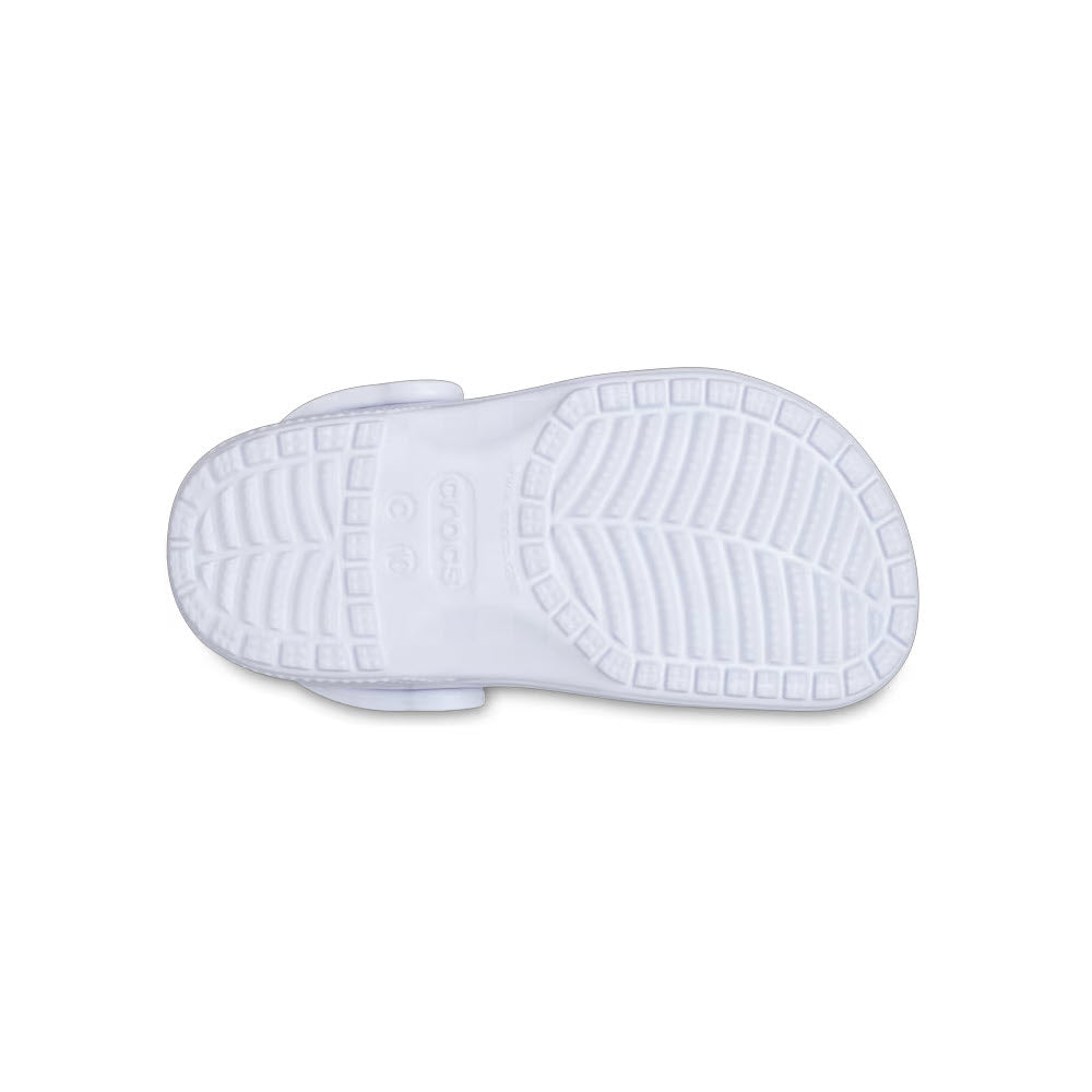 A photo showing the tread and sole pattern of a white Crocs CROCS CLASSIC CLOG DREAMSCAPE - TODDLER, displaying its textured design and logo, emphasizing comfort and support.