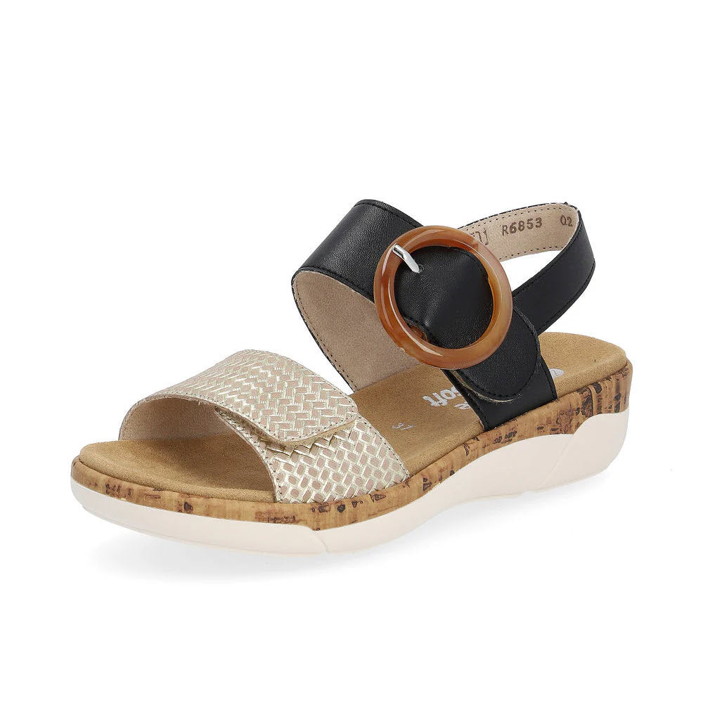 The REMONTE BIG BUCKLE COMFORT SANDAL BLACK/GOLD for women by Remonte features a stylish design with a cork-textured wedge sole, a white textured front strap, a sleek black leather ankle strap, and a striking large brown circular buckle.