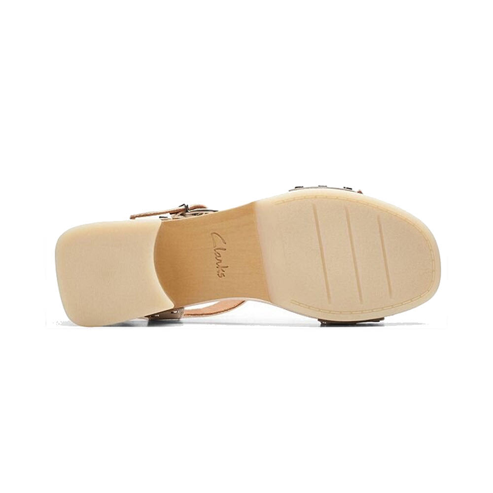 Bottom view of a white Clarks Sivanne Bay clog with a block heel and the brand name &quot;Clarks&quot; printed on the sole. The sole features three horizontal grooves for traction, perfectly complemented by black leather uppers and a comfortable Contour Cushion footbed.