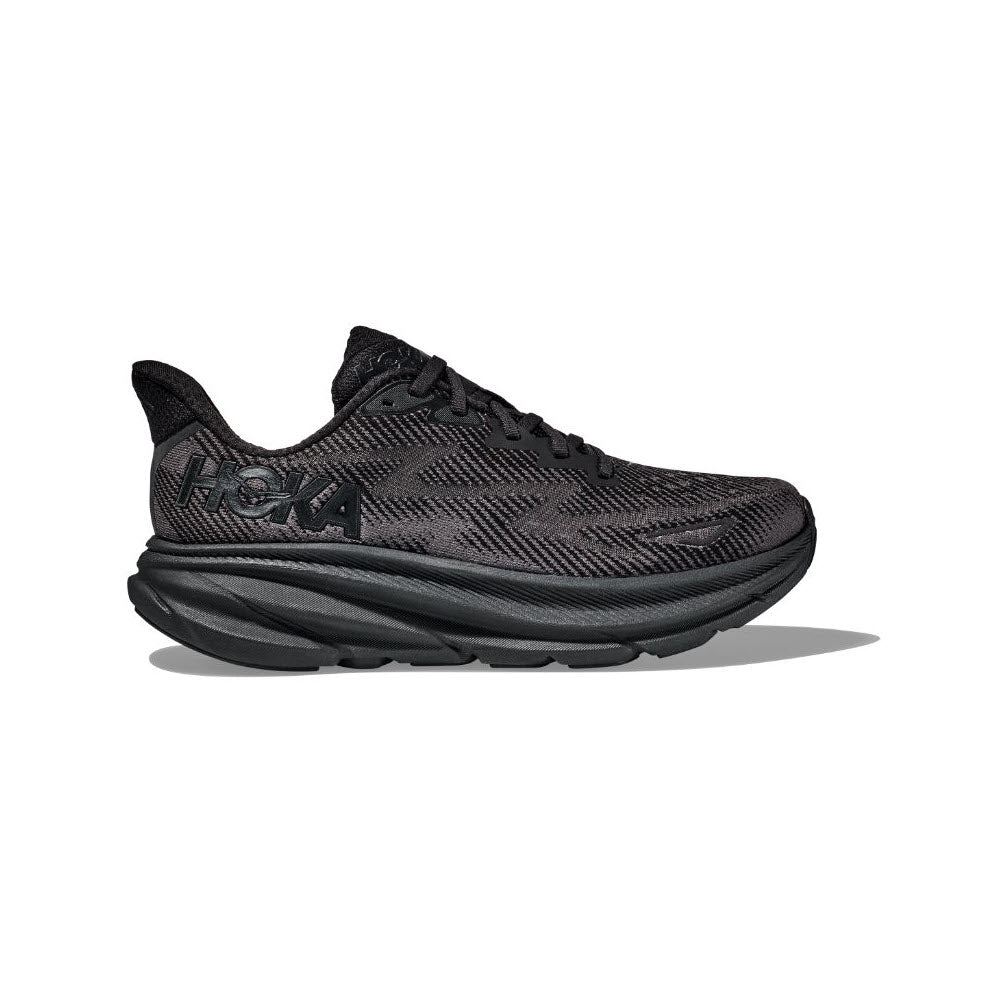 A black athletic shoe with a textured upper and letters reading "HOKA" on the side, featuring a thick cushioned sole. This Hoka Clifton 9 GTX Black/Black - Mens is a lightweight cushioned shoe equipped with responsive foam for superior comfort and performance.