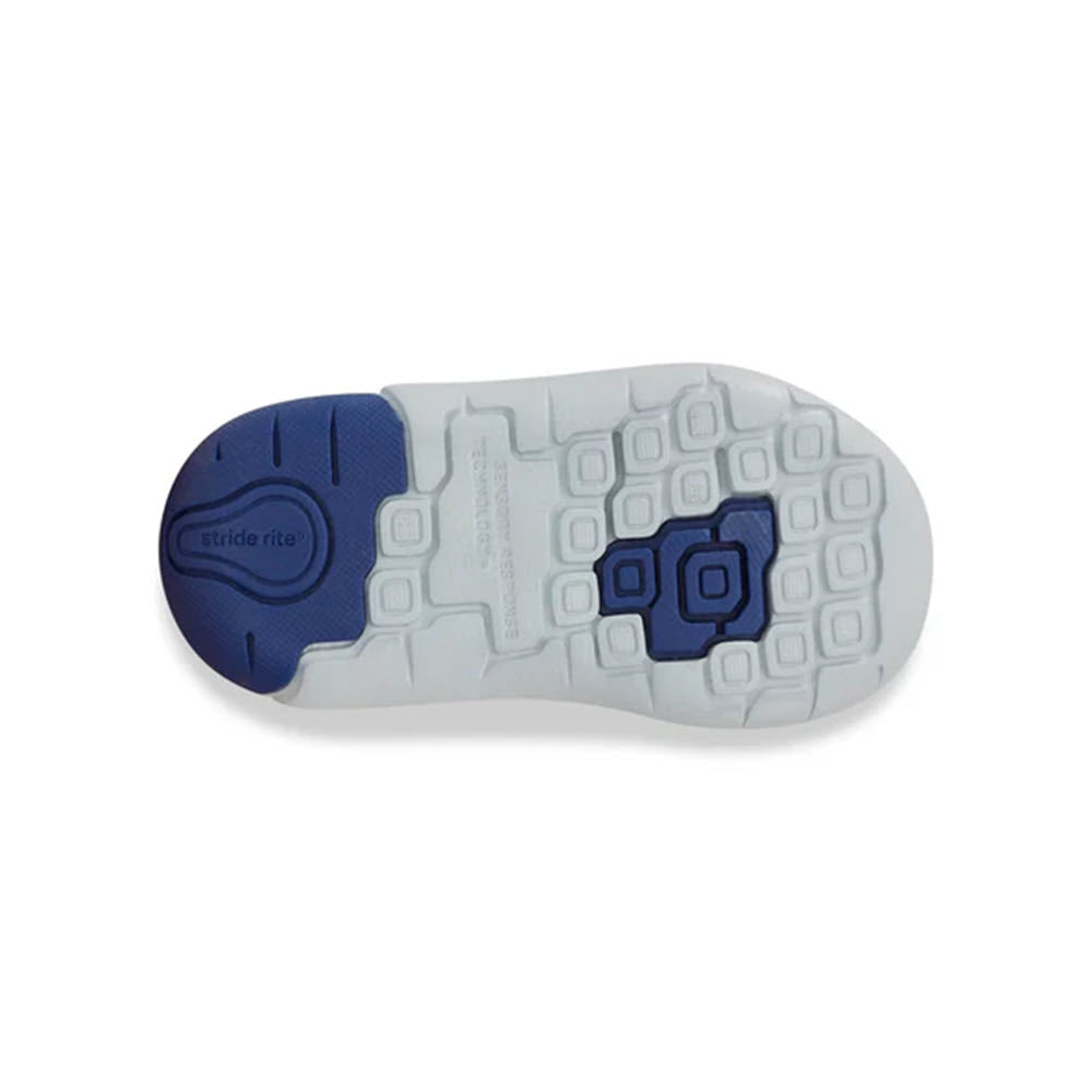 The image shows the sole of a baby shoe from the STRIDE RITE SRT IAN BLUE - KIDS line by Stride Rite. The sole is white with blue accents, featuring a textured tread pattern and a circular &quot;stride rite&quot; logo. These sporty shoes also include a memory foam footbed for added comfort.