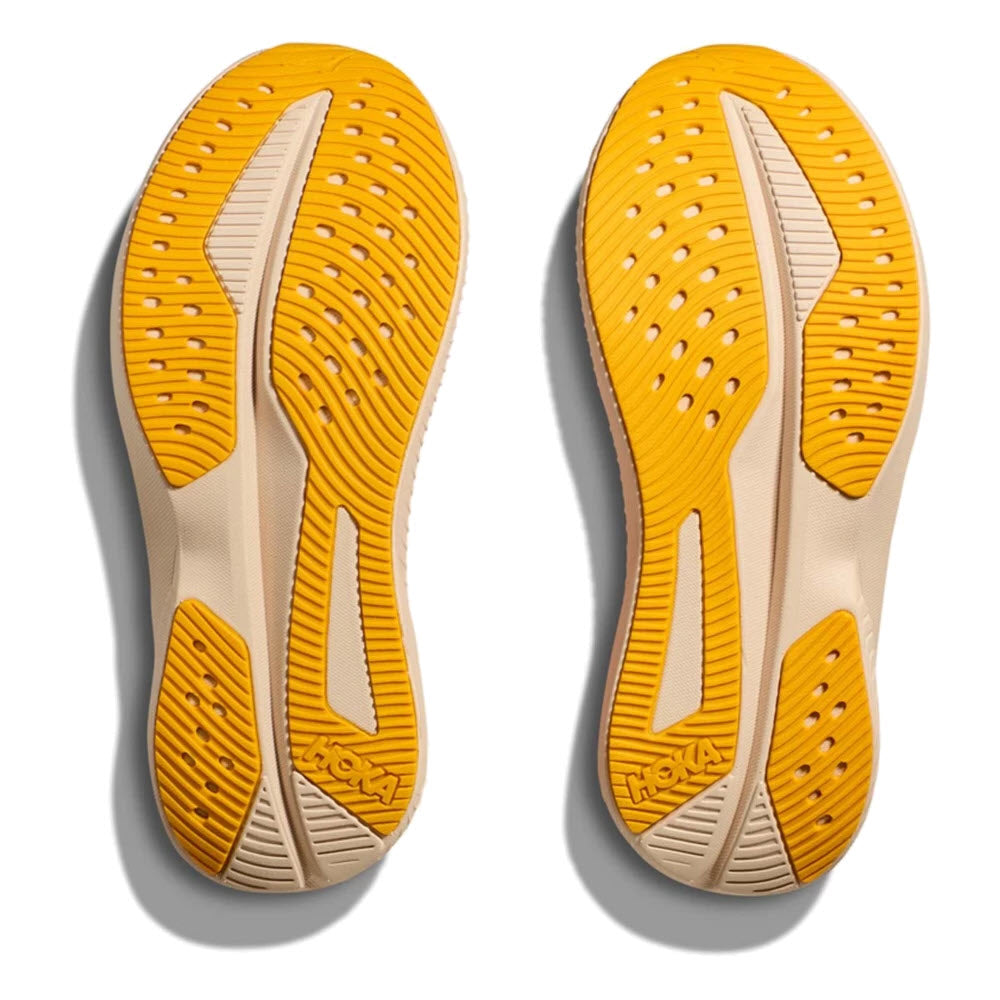 A pair of ultramarine and tangerine Hoka shoe soles with textured patterns and perforations arranged side by side, viewed from below, showcasing the extra durability perfect for HOKA MACH 6 YOUTH – KIDS running shoes.