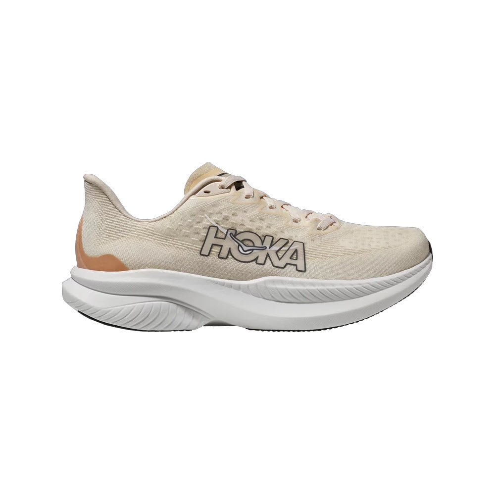 The HOKA MACH 6 in Eggnog/Vanilla for women, featuring &quot;HOKA&quot; written on the side, comes in a beige color with a thick white sole and a structured design, making it ideal for road running or daily training.