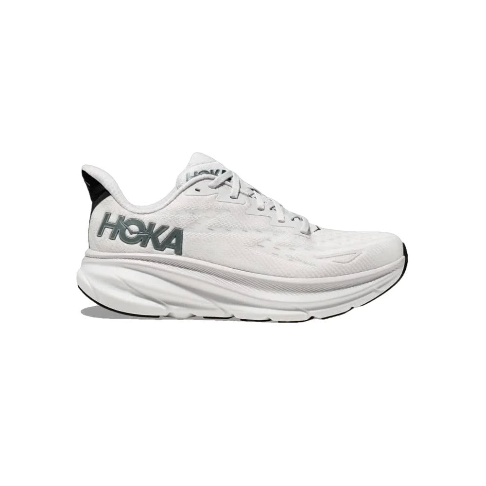 The HOKA Clifton 9 in Nimbus Cloud/Steel Wool for men is a white athletic shoe with the iconic grey Hoka logo on the side. It features a thick, cushioned sole with responsive foam and black detailing on the back, offering exceptional comfort and support for your athletic needs.