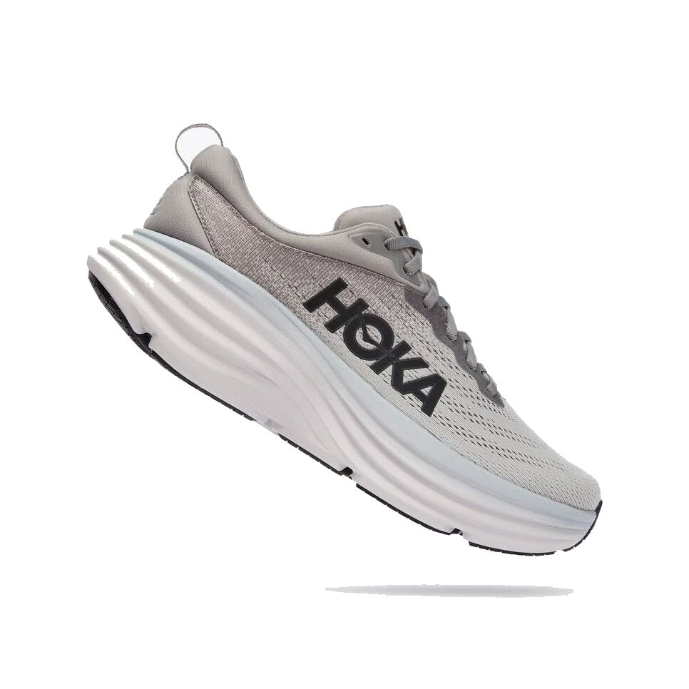 The HOKA BONDI 8 SHARKSKIN/HARBOR MIST for men features a thick, textured white sole with the brand&#39;s name prominently displayed in large black letters on the side and an extended heel geometry for improved stability.